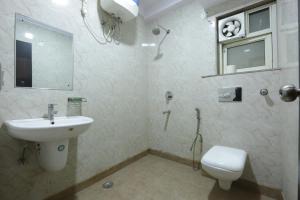 een badkamer met een wastafel, een toilet en een spiegel bij Hotel Mayank Plaza-Near IGI Airport Terminal-3 in New Delhi
