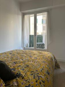 a bedroom with a bed with a yellow comforter and a window at Joli F2, 7 min de la gare in Cannes