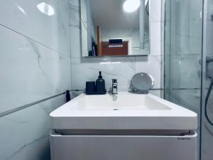 La salle de bains est pourvue d'un lavabo blanc et d'un miroir. dans l'établissement Private 2 Bed Guest House - Van Parking, M25 & A1 connections, à Potters Bar
