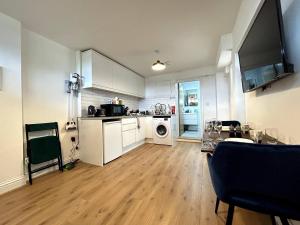 cocina con armarios blancos y suelo de madera en Private 2 Bed Guest House - Van Parking, M25 & A1 connections, en Potters Bar