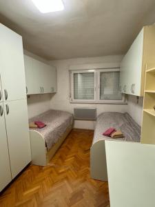 2 Betten in einem kleinen Zimmer mit weißen Schränken in der Unterkunft Apartman Sunnyplace in Mostar