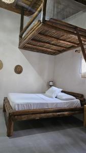 a bedroom with a large bed with a wooden frame at Mano a Mano Eco Hostal in Las Peñitas