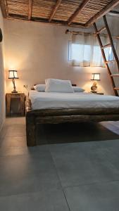 a bed in a room with two lamps on a table at Mano a Mano Eco Hostal in Las Peñitas