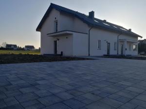 a white building with a brick driveway in front of it at Apartamenty na 102 in Iława
