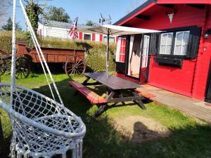 ein rotes Haus mit einem Picknicktisch und einem Regenschirm in der Unterkunft Chalet Opale Texas in Hermelinghen