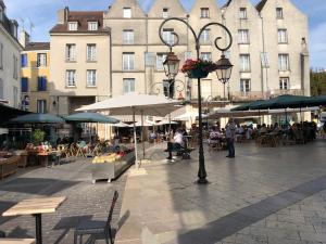 una calle de la ciudad con mesas, sombrillas y edificios en Appartement Art moderne entre Disney et Paris, en Lagny