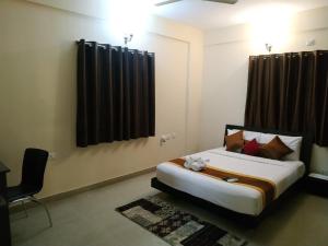 a bedroom with a bed and a chair in it at ADI HOSPITALITY AND TOURS PRIVATE LIMITED in Bangalore