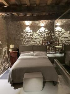 - une chambre avec un grand lit et un mur en pierre dans l'établissement Dalle Stelle, à Ficulle