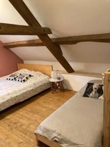 2 Betten in einem Zimmer mit Holzbalken in der Unterkunft Maison, Le Champ du Rossignol in Beuvron-en-Auge