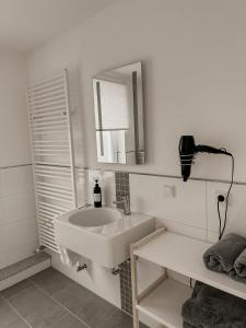 a white bathroom with a sink and a mirror at Haus am Waldrand in Bad Hersfeld