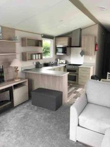 a large kitchen with a white couch and a chair at Immaculate 2020 Caravan on Newquay Holiday Park in Newquay