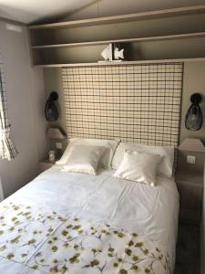 a bed with white sheets and pillows in a bedroom at Immaculate 2020 Caravan on Newquay Holiday Park in Newquay