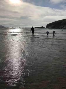three people walking in the water on the beach at Immaculate 2020 Caravan on Newquay Holiday Park in Newquay
