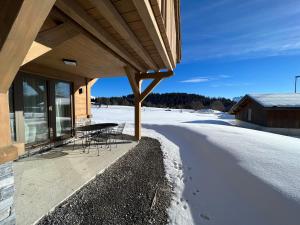 a porch of a house with a table and chairs in the snow at Chalet Clémence in Taninges