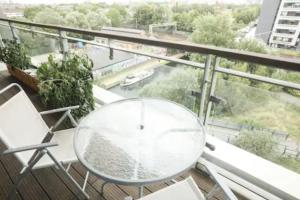 a glass table and chairs on a balcony at Bedroom & dedicated workspace in spacious flat in London