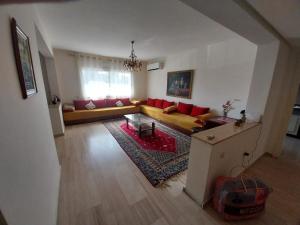 Appartement Hay Riad في الرباط: غرفة معيشة مع أريكة صفراء ووسائد حمراء