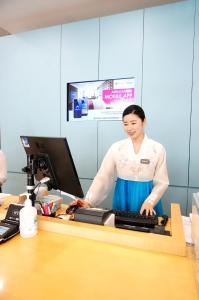 a woman standing next to a desk with a keyboard at ibis Ambassador Insadong in Seoul