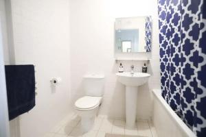 a white bathroom with a toilet and a sink at Bedroom & dedicated workspace in spacious flat in London