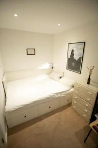 a white bed in a room with a dresser at Bedroom & dedicated workspace in spacious flat in London