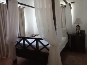 1 dormitorio con 1 cama con cortinas blancas en Hermoso apartamento de playa en perla marina Sosua - Cabarete, en Sosúa