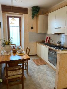 una cocina con mesa de madera y una cocina con armarios blancos. en Casa Milena, en San Gimignano