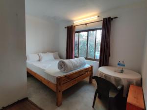 a bedroom with a bed and a chair and a window at Hotel Gogreen Kattike Pvt. Ltd. in Nagarkot