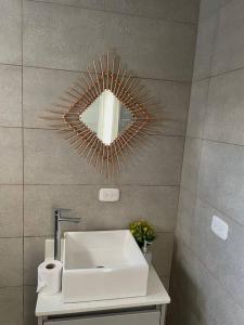 a bathroom with a white sink and a mirror at Alojamiento Kim House Orotina in Orotina