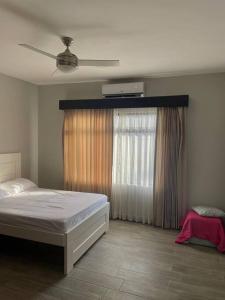 una camera con un letto bianco e una finestra di Alojamiento Kim House Orotina a Orotina