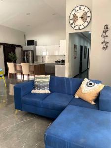 un divano blu in soggiorno con orologio di Alojamiento Kim House Orotina a Orotina