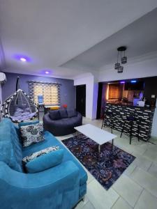 a living room with a blue couch and a table at Asfranz Apartment Luxury One-Bedroom with Private Garden in Abuja