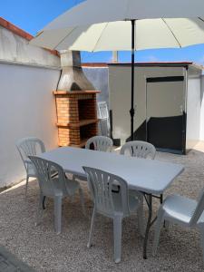 una mesa y sillas con una sombrilla en el patio en Maison de vacances, en Pombal