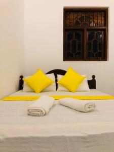 ein Bett mit gelben und weißen Kissen darauf in der Unterkunft Leyon-Tourist Inn in Negombo