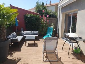 un patio con sillas, un sofá y una mesa en Joli appartement 50 m2 classé 3 etoiles avec terrasse et jardin, en La Rochelle