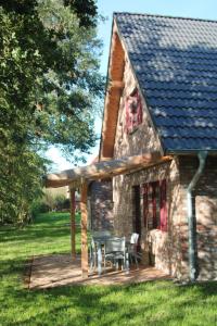 uma casa de pedra com um deque, uma mesa e cadeiras em Ferienhaus Luv em Pellworm