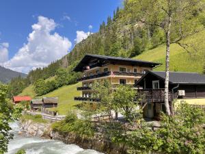 a building on a hill next to a river at Stubnerhof in Bad Gastein