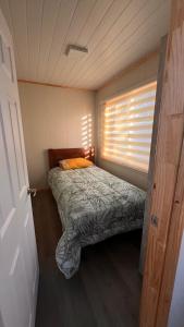 a small bedroom with a bed and a window at Pewma Apart Hotel in Chillán