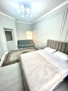 a bedroom with a large bed and a couch at Keruen Saray Apartments 2 in Türkistan