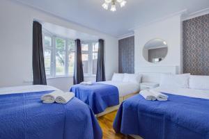 um quarto de hotel com três camas com lençóis azuis em Streatham Hotel em Londres
