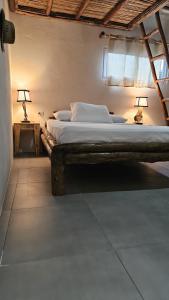 a bedroom with a large bed with a wooden frame at Mano a Mano Eco Hostal in Las Peñitas