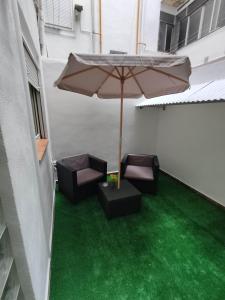 an umbrella and chairs on a patio with green grass at benimaclet delux3 in Valencia