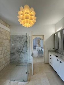 ein Bad mit einer Dusche und einem Kronleuchter in der Unterkunft Dar Daniella - Small Design Luxury Hotel in Tabarca