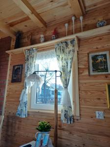 una ventana en una cabaña de madera con una cortina en Magia Krutyni Domek nr2, en Ukta