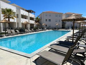 a swimming pool with lounge chairs and umbrellas at Studio en bord de mer sur Costa Serena N54 in Linguizzetta