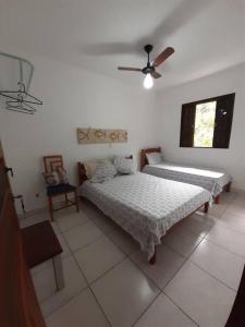 ein Schlafzimmer mit zwei Betten und einem Deckenventilator in der Unterkunft Casa sobreposta alta em Boiçucanga - São Sebastião in São Sebastião