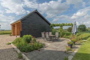 een zwarte schuur met een tafel en stoelen en een paraplu bij 't Kruushuus in Welsum