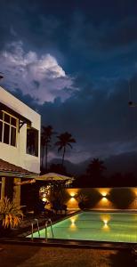 a swimming pool in front of a house at night at Luna Waves in Negombo