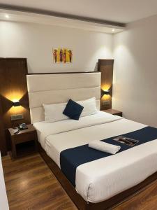 ムンバイにあるHotel the pacific Chakalaのベッドルーム(白い大型ベッド、ランプ2つ付)