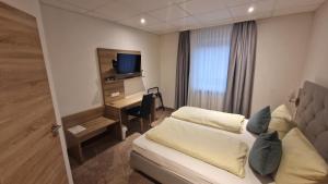 ein Hotelzimmer mit einem Bett und einem Schreibtisch mit einem TV in der Unterkunft Schwarzer Adler - Hotel Garni in Ipsheim