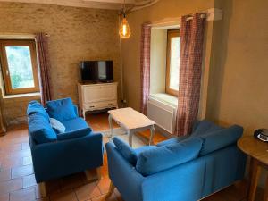 uma sala de estar com dois sofás azuis e uma mesa em Gite Introvigne Sarlat em Sarlat-la-Canéda