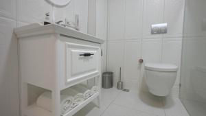 a white bathroom with a toilet and a sink at Pertevniyal Aziziye Hotel in Konya